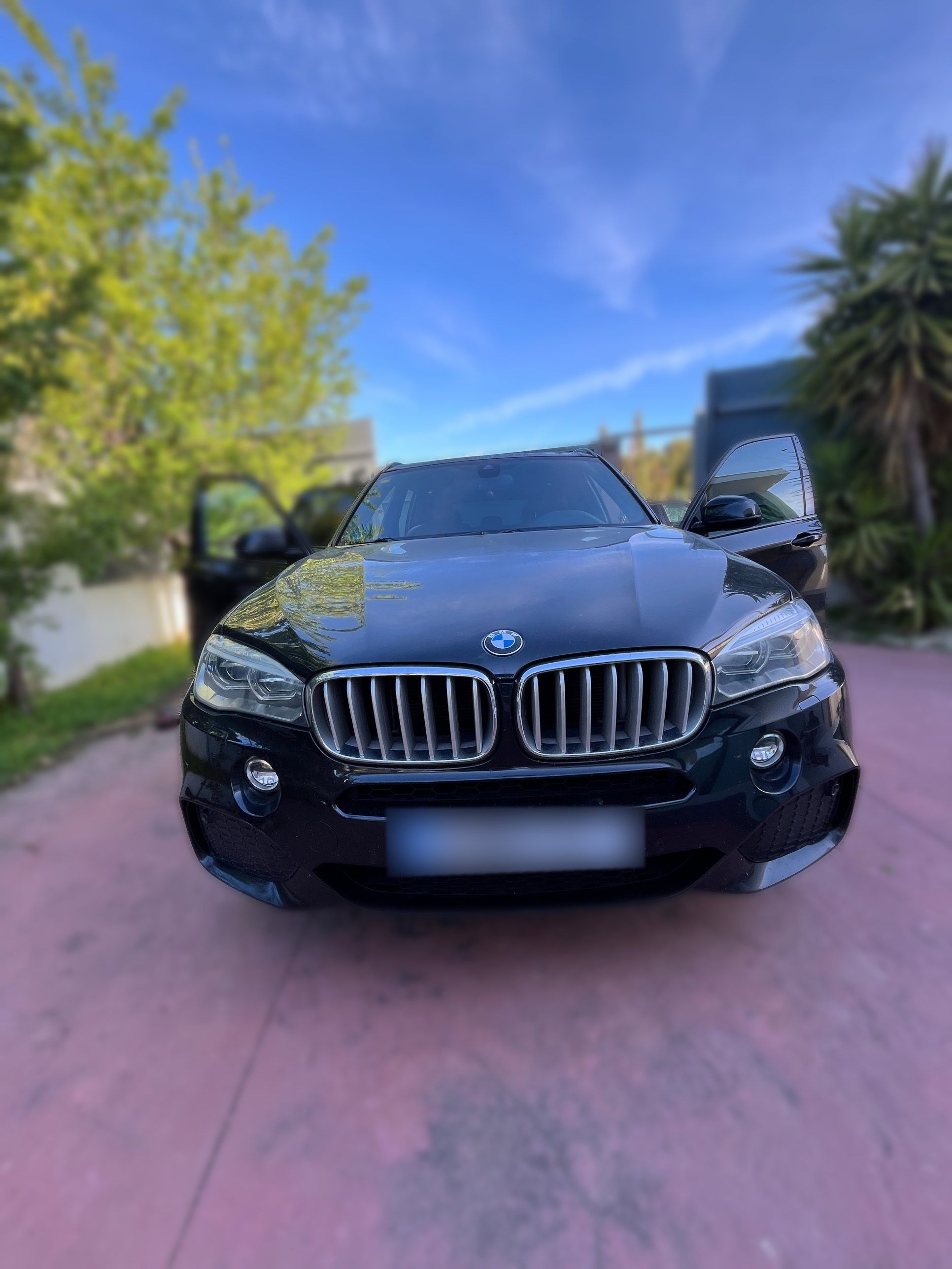 Frontal de un BMW X5 negro recién lavado, con la parrilla y el capó brillantes