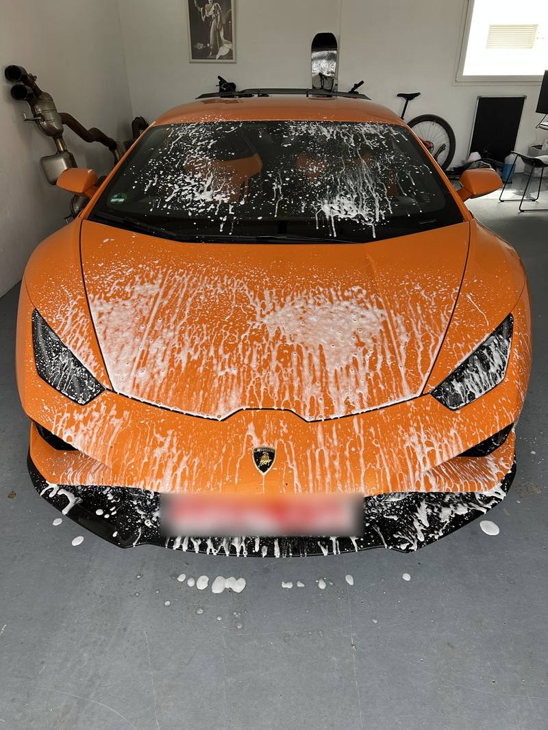 Lamborghini naranja cubierto de espuma durante el lavado a domicilio