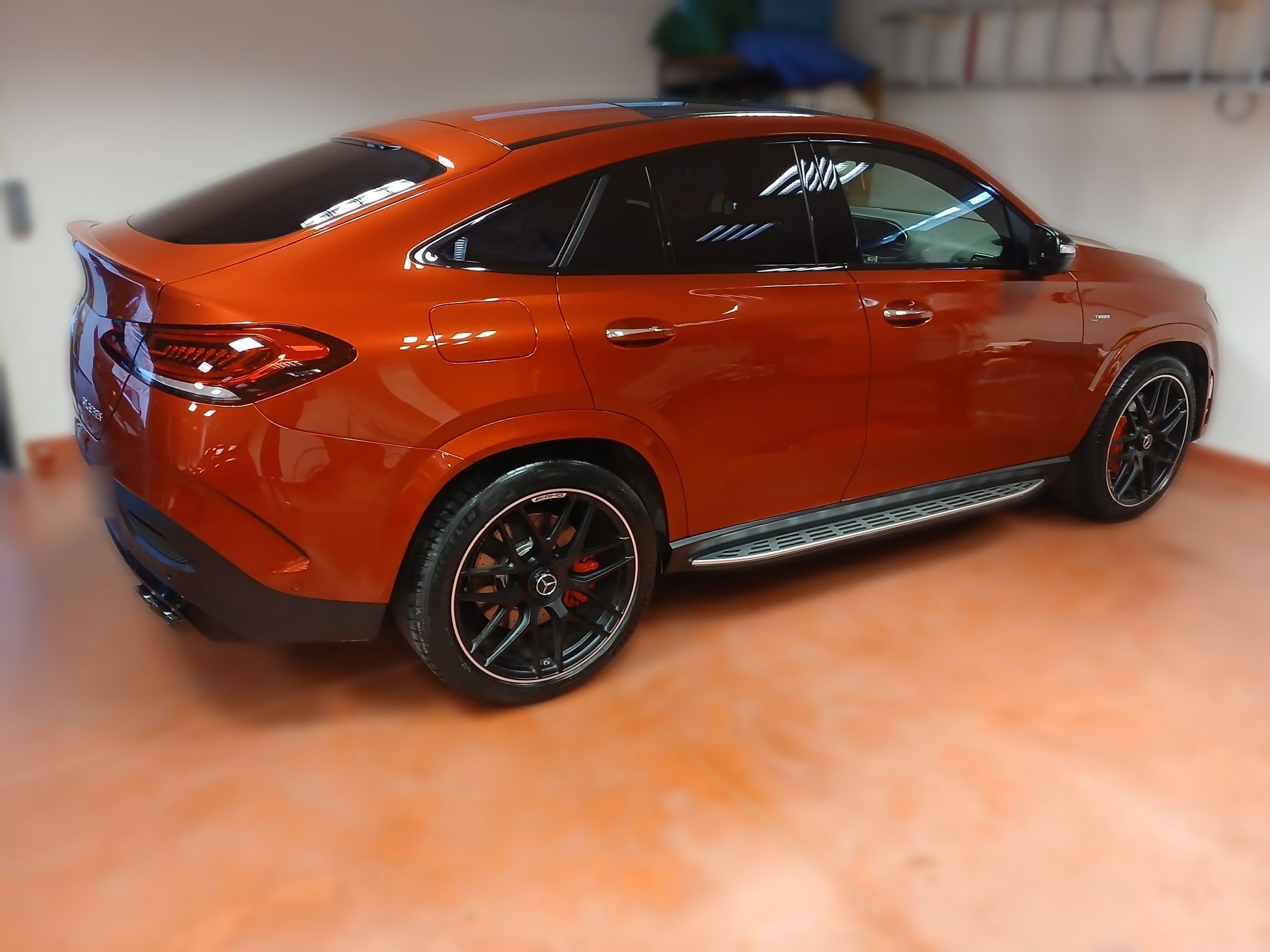 Mercedes-AMG GLE Coupé naranja brillante recién lavado, vista trasera de tres cuartos en un garaje