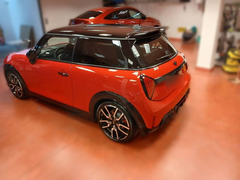 Mini Cooper rojo con techo negro recién lavado, vista trasera de tres cuartos