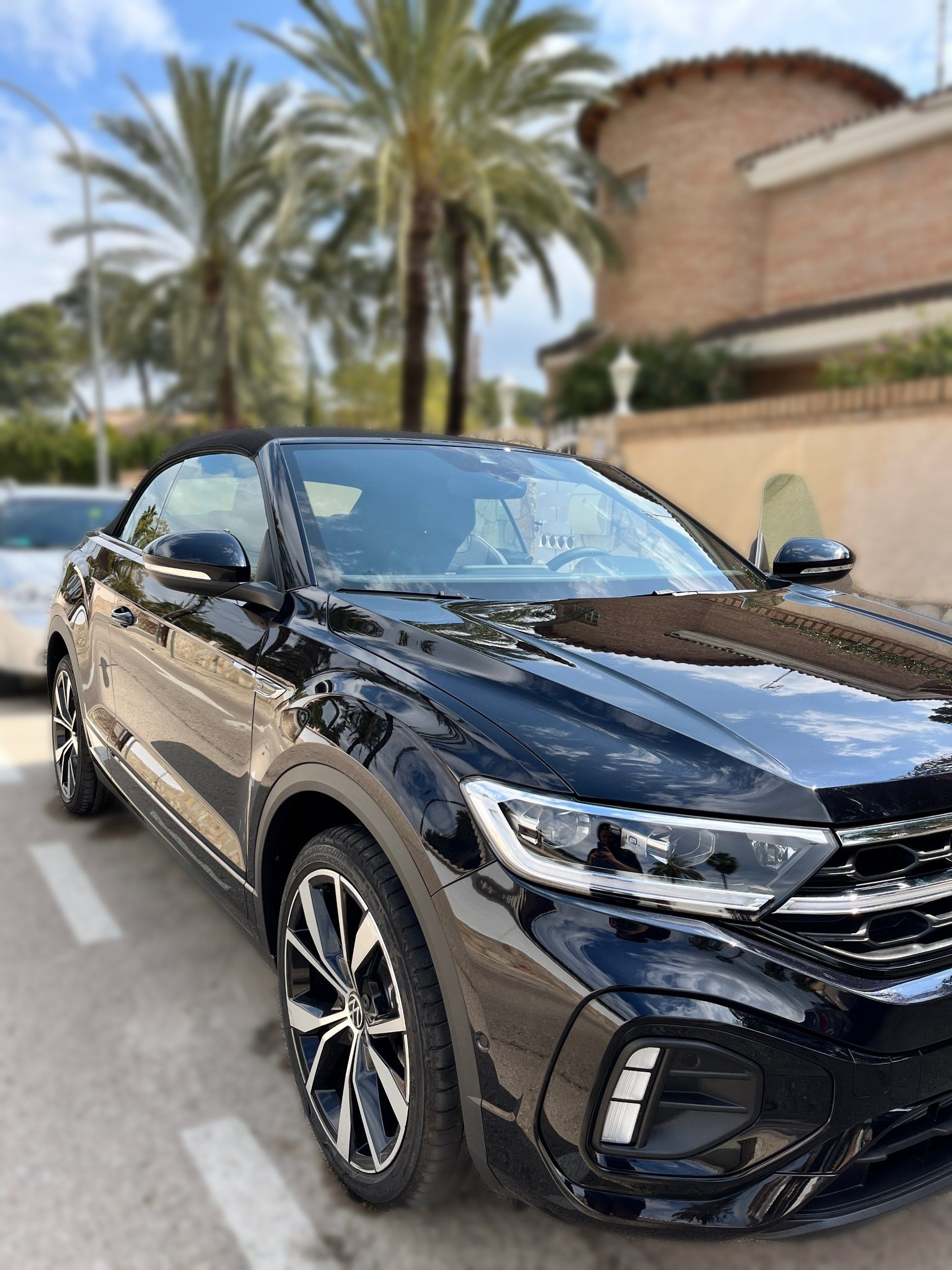 Volkswagen T-Roc Cabrio negro recién lavado, vista frontal de tres cuartos con la carrocería brillante