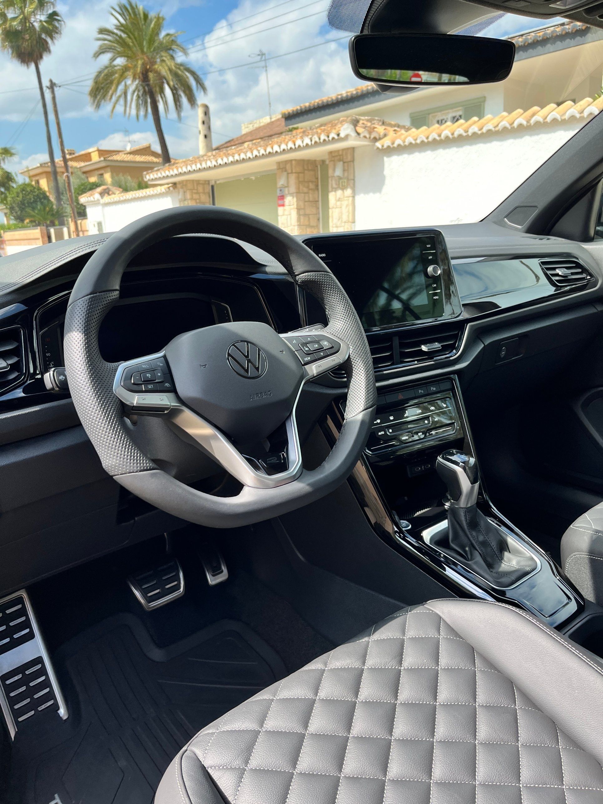 Interior de un Volkswagen T-Roc limpio: volante, consola central y asiento acolchado gris